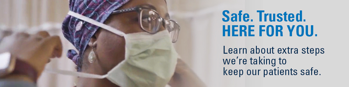 Woman health care provider putting on a mask. Text: Safe. Trusted. Here for you. learn about extra steps we're taking to keep our patients safe.